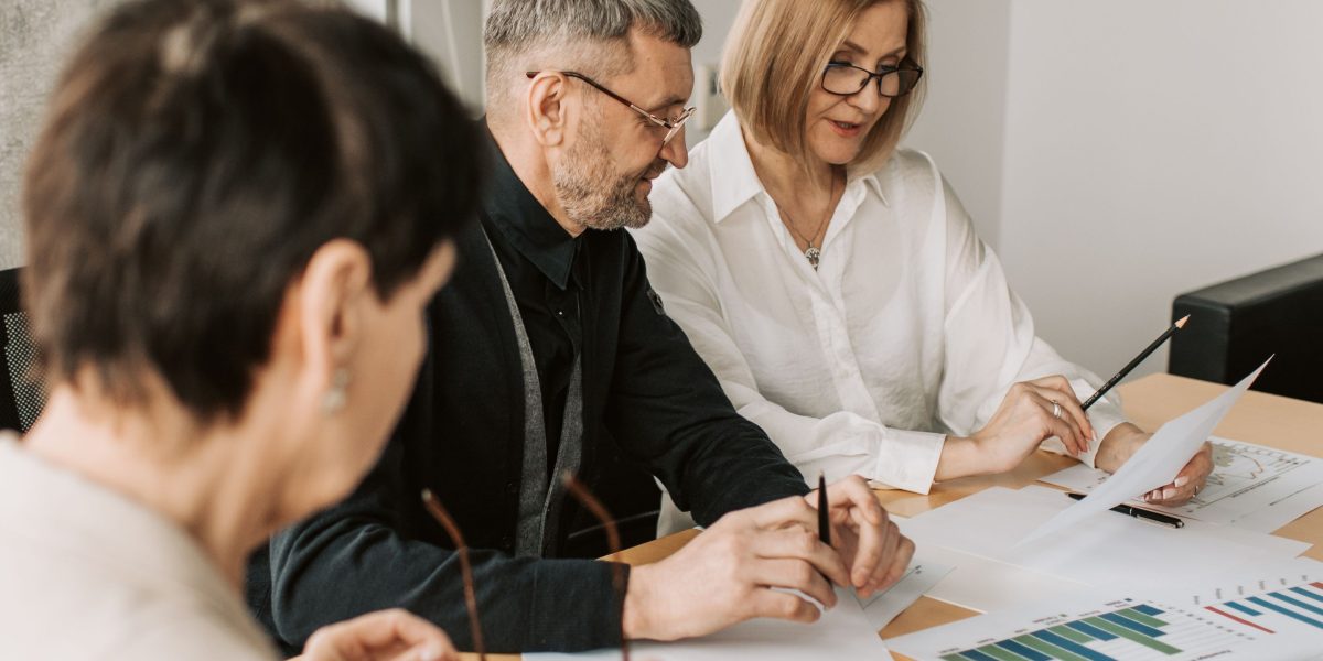 Professionals in a business meeting, actively discussing and reviewing regulatory documents.