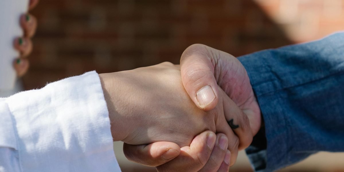 Two professionals shaking hands, symbolizing agreement and trust in a financial or business context.