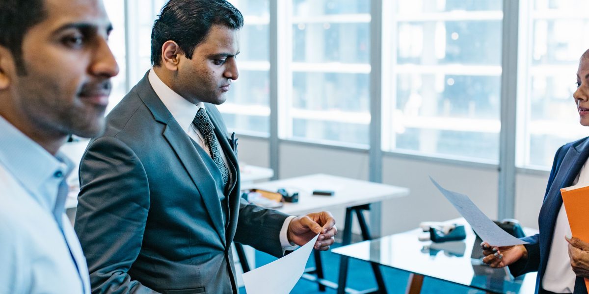 Two professionals meticulously reviewing various documents, symbolizing the thorough due diligence process required when selecting an investment advisor.