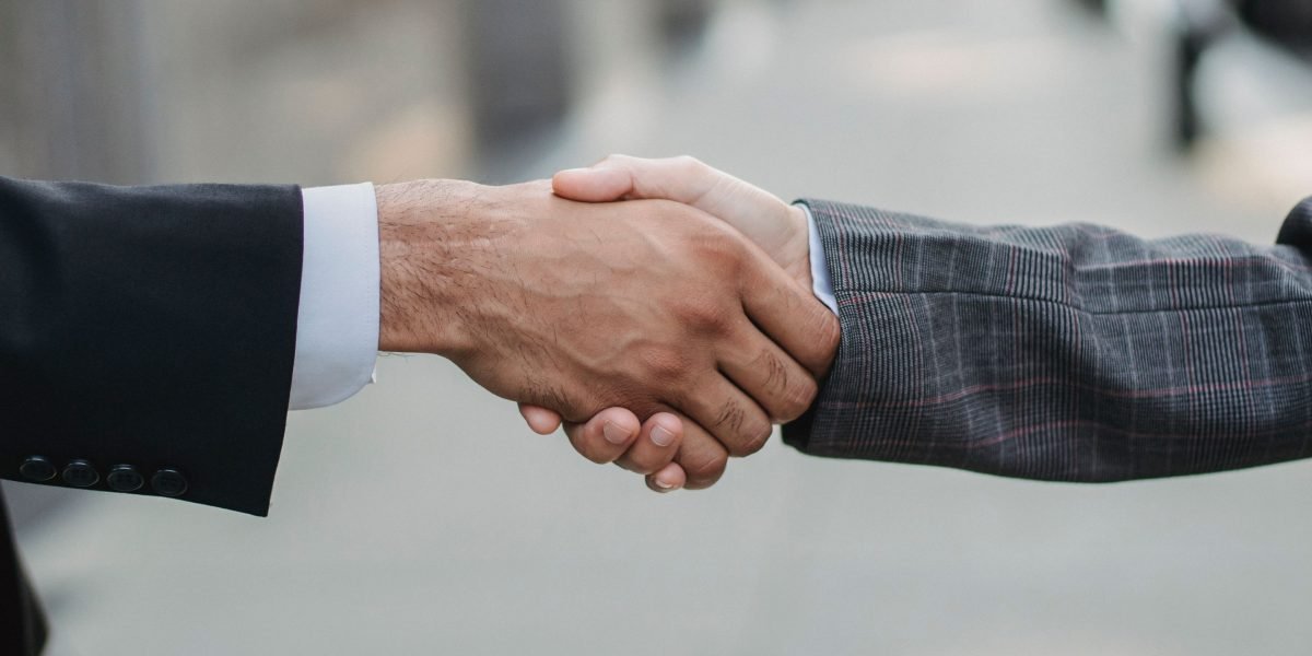 Two business professionals shaking hands over a signed contract, representing the finalization of an agreement with an investment advisor.